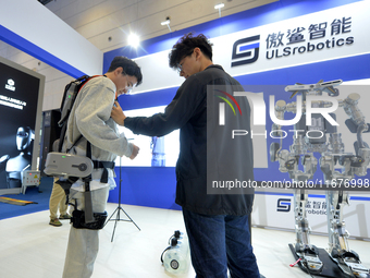 An audience experiences an intelligent electric upper limb exoskeleton robot at the 2024 China International Consumer Electronics Expo in Qi...