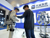 An audience experiences an intelligent electric upper limb exoskeleton robot at the 2024 China International Consumer Electronics Expo in Qi...