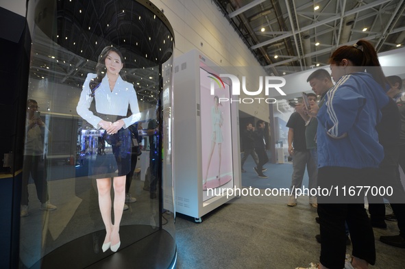 Visitors look at an AI holographic transparent capsule at the 2024 China International Consumer Electronics Expo in Qingdao, China, on Octob...