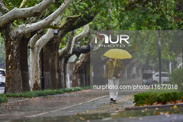 People wear thick clothes and walk in the rain in Qingzhou, China, on October 18, 2024. 