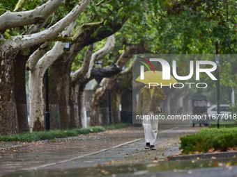 People wear thick clothes and walk in the rain in Qingzhou, China, on October 18, 2024. (