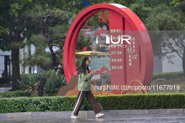 People wear thick clothes and walk in the rain in Qingzhou, China, on October 18, 2024. 