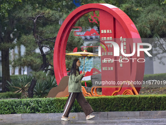 People wear thick clothes and walk in the rain in Qingzhou, China, on October 18, 2024. (