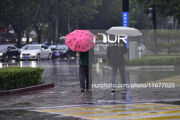 People wear thick clothes and walk in the rain in Qingzhou, China, on October 18, 2024. 