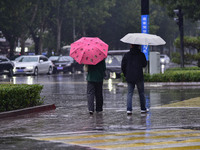 People wear thick clothes and walk in the rain in Qingzhou, China, on October 18, 2024. (