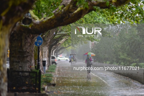 People wear thick clothes and walk in the rain in Qingzhou, China, on October 18, 2024. 