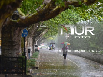 People wear thick clothes and walk in the rain in Qingzhou, China, on October 18, 2024. (