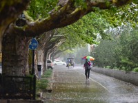 People wear thick clothes and walk in the rain in Qingzhou, China, on October 18, 2024. (