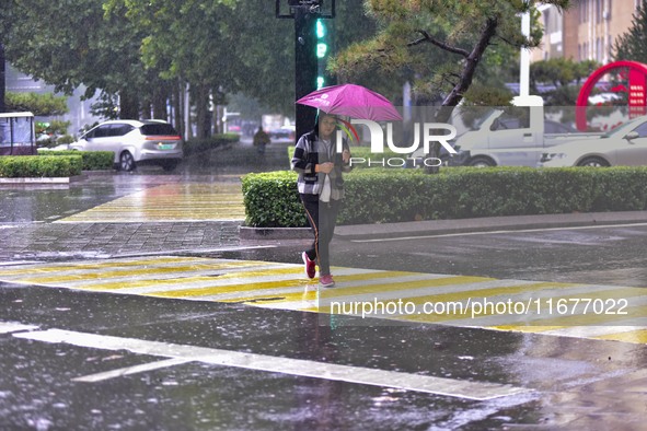 People wear thick clothes and walk in the rain in Qingzhou, China, on October 18, 2024. 