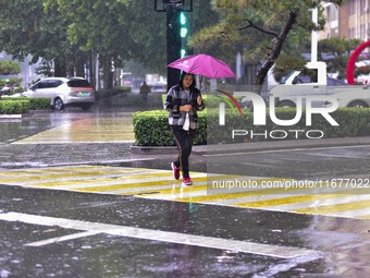 People wear thick clothes and walk in the rain in Qingzhou, China, on October 18, 2024. (