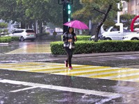 People wear thick clothes and walk in the rain in Qingzhou, China, on October 18, 2024. (