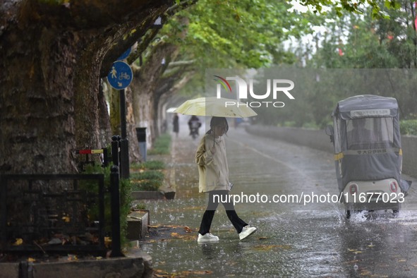 People wear thick clothes and walk in the rain in Qingzhou, China, on October 18, 2024. 