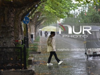 People wear thick clothes and walk in the rain in Qingzhou, China, on October 18, 2024. (