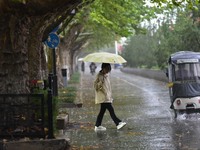 People wear thick clothes and walk in the rain in Qingzhou, China, on October 18, 2024. (