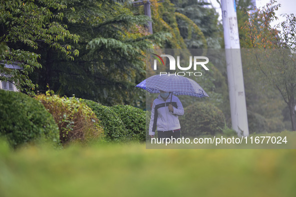 People wear thick clothes and walk in the rain in Qingzhou, China, on October 18, 2024. 