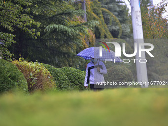 People wear thick clothes and walk in the rain in Qingzhou, China, on October 18, 2024. (