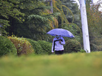 People wear thick clothes and walk in the rain in Qingzhou, China, on October 18, 2024. (