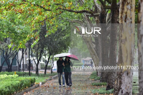 People wear thick clothes and walk in the rain in Qingzhou, China, on October 18, 2024. 