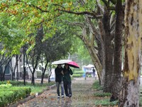 People wear thick clothes and walk in the rain in Qingzhou, China, on October 18, 2024. (