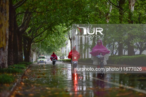 People wear thick clothes and ride in the rain in Qingzhou, China, on October 18, 2024. 