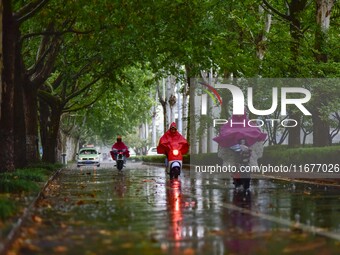 People wear thick clothes and ride in the rain in Qingzhou, China, on October 18, 2024. (