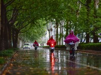 People wear thick clothes and ride in the rain in Qingzhou, China, on October 18, 2024. (