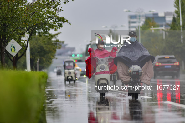 People wear thick clothes and ride in the rain in Qingzhou, China, on October 18, 2024. 