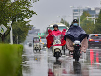 People wear thick clothes and ride in the rain in Qingzhou, China, on October 18, 2024. (