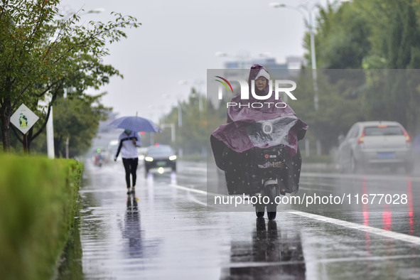 People wear thick clothes and ride in the rain in Qingzhou, China, on October 18, 2024. 