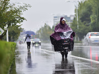 People wear thick clothes and ride in the rain in Qingzhou, China, on October 18, 2024. (