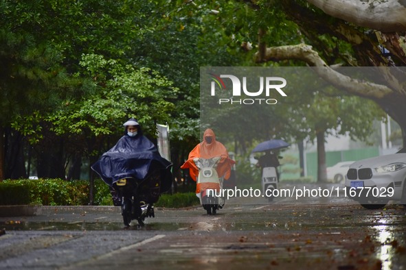 People wear thick clothes and ride in the rain in Qingzhou, China, on October 18, 2024. 