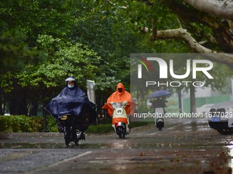 People wear thick clothes and ride in the rain in Qingzhou, China, on October 18, 2024. (