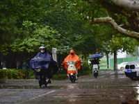 People wear thick clothes and ride in the rain in Qingzhou, China, on October 18, 2024. (