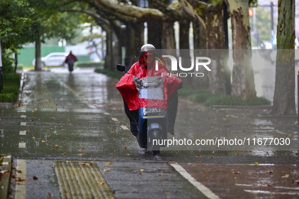 People wear thick clothes and ride in the rain in Qingzhou, China, on October 18, 2024. 