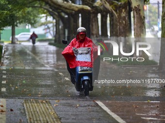 People wear thick clothes and ride in the rain in Qingzhou, China, on October 18, 2024. (