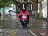 People wear thick clothes and ride in the rain in Qingzhou, China, on October 18, 2024. (