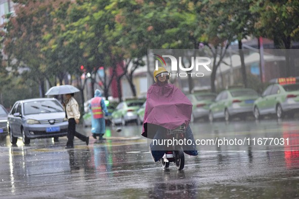 People wear thick clothes and ride in the rain in Qingzhou, China, on October 18, 2024. 