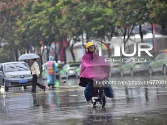 People wear thick clothes and ride in the rain in Qingzhou, China, on October 18, 2024. (