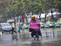 People wear thick clothes and ride in the rain in Qingzhou, China, on October 18, 2024. (