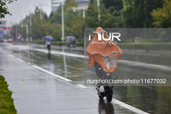 People wear thick clothes and ride in the rain in Qingzhou, China, on October 18, 2024. 