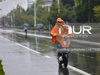 People wear thick clothes and ride in the rain in Qingzhou, China, on October 18, 2024. (