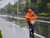 People wear thick clothes and ride in the rain in Qingzhou, China, on October 18, 2024. (