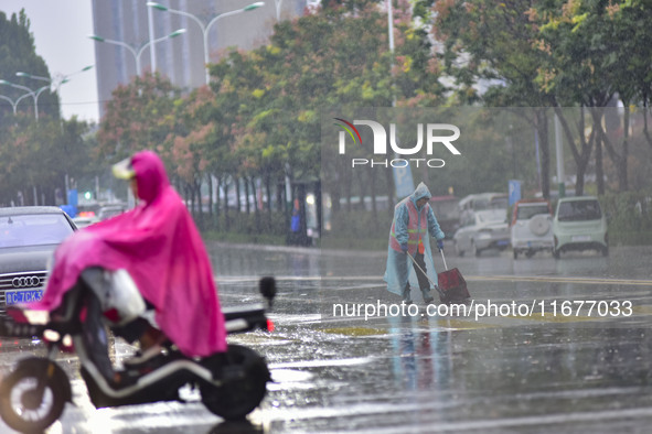 People wear thick clothes and ride in the rain in Qingzhou, China, on October 18, 2024. 