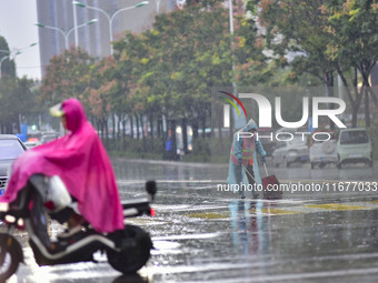 People wear thick clothes and ride in the rain in Qingzhou, China, on October 18, 2024. (