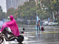 People wear thick clothes and ride in the rain in Qingzhou, China, on October 18, 2024. (