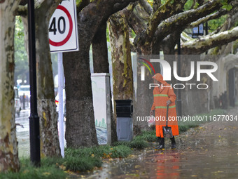 A sanitation worker braves rain to clean up garbage on a street in Qingzhou, China, on October 18, 2024. (