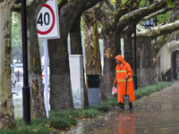 A sanitation worker braves rain to clean up garbage on a street in Qingzhou, China, on October 18, 2024. (