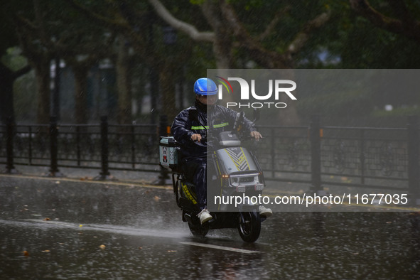 A food delivery man rides in the rain on a street in Qingzhou, China, on October 18, 2024. 