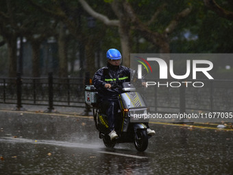 A food delivery man rides in the rain on a street in Qingzhou, China, on October 18, 2024. (