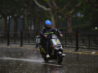 A food delivery man rides in the rain on a street in Qingzhou, China, on October 18, 2024. (